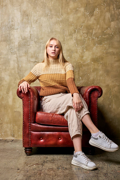 portrait of confident caucasian female sitting on leather sofa - Zdjęcie, obraz