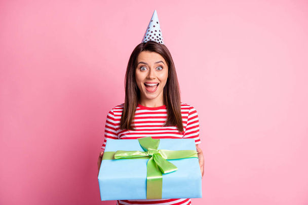 Photo portrait of happy surprised girl receiving wrapped present wearing festive cap smiling isolated on pastel pink color background - Foto, immagini