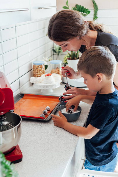 γυναίκα και γιος μαγειρεύουν γλυκά κέικ στην κουζίνα - Φωτογραφία, εικόνα