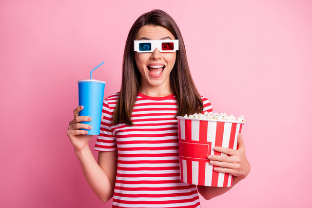 Photo portrait of surprised cheerful girl wearing 3d glasses holding pop corn cup of fizzy drink isolated on pastel pink color background - Fotografie, Obrázek