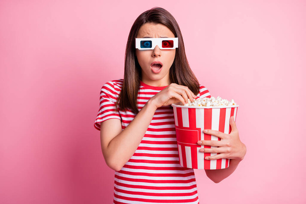 Photo portrait of shocked girl wearing 3d glasses keeping box with pop corn watching film isolated on pastel pink color background - Zdjęcie, obraz
