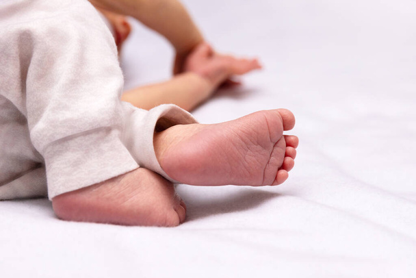 The little feet of a baby in panties lie on the bed. Selective focus. - Zdjęcie, obraz