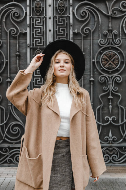 blonde in a brown coat with black hat posing, smiling, upset - Photo, image