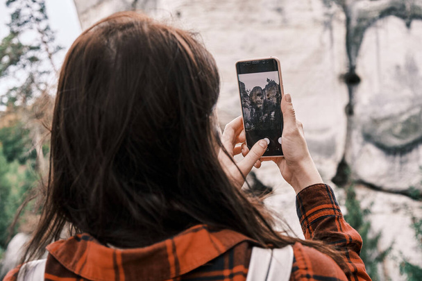 Zblízka žena v červené košili dělat fotku nebo video z kamene a lesa pomocí svého smartphonu. Turisme koncept. Turistika v horách - Fotografie, Obrázek