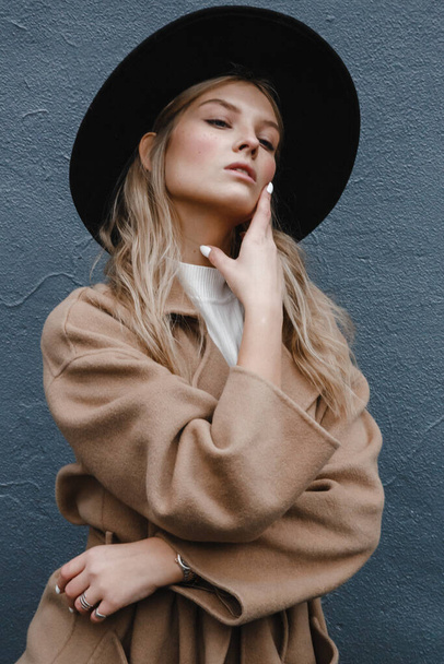 blonde dans un manteau marron avec chapeau noir posant, souriant, bouleversé - Photo, image