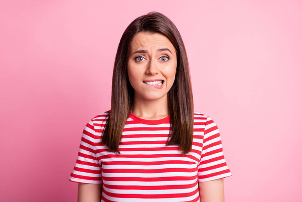 Portrait of stressed young lady bite lip wear tabby red white t-shirt isolated on pastel pink color background - Foto, Imagem