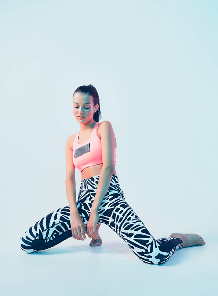 Sporty fit girl in stylish sportswear posing in neon light. Leggings for effective workout, healthy sport lifestyle - Foto, afbeelding