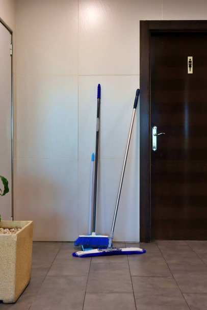 broom and mop in front of the toilet door. Cleaning service in restaurants and hotels. Cleaning employees - Foto, immagini