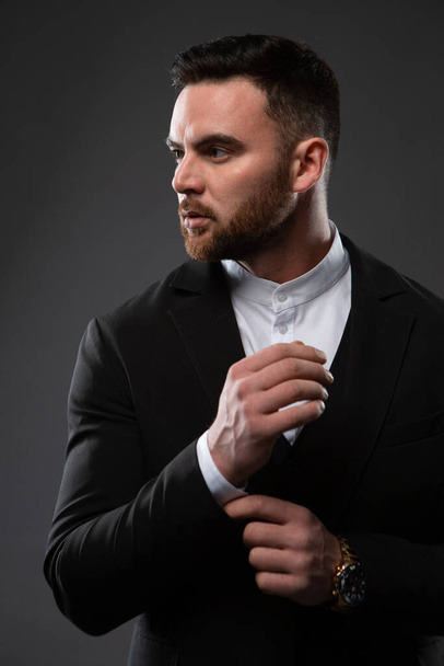 a handsome man in a black suit and white shirt. A businessman standing on a black background. Close-up photo - Foto, Imagem
