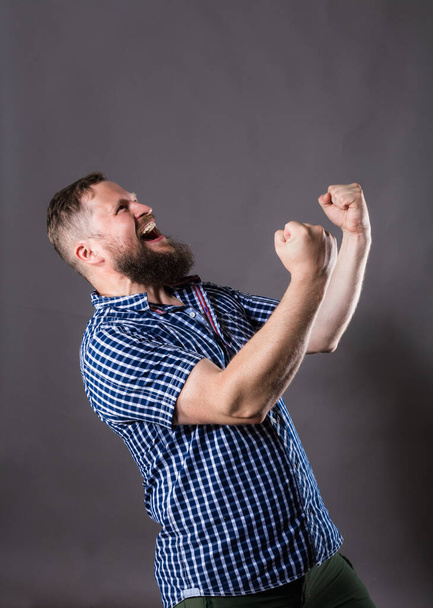 Joyful bearded man in shirt celebrating the victory - Fotoğraf, Görsel