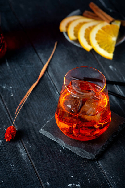 An Aperol syringe with orange and ice in glass on a dark wooden background - Foto, immagini