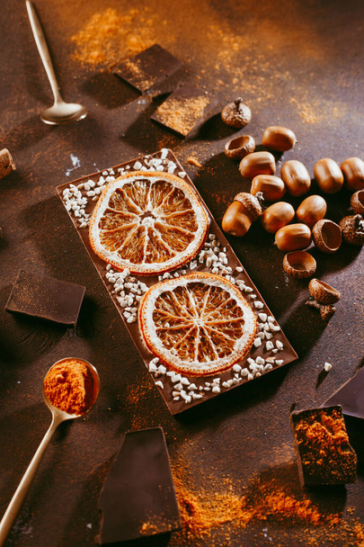 Candied orange slices in chocolate lie on a dark brown background, next to Cutlery. Slate background. - Zdjęcie, obraz