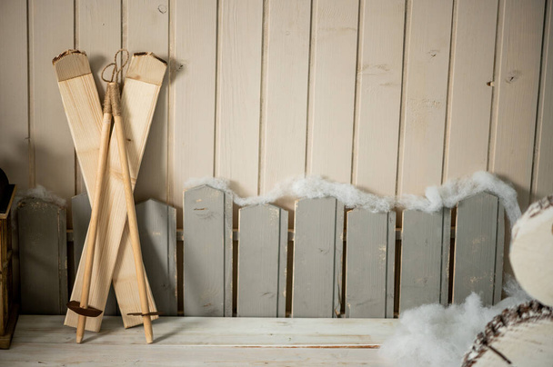 Estúdio de Natal decorativo com uma casa com porta azul, banco de madeira e esquis, boneco de neve, nuvens falsas e neve - Foto, Imagem