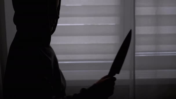 Silueta osamělého dítěte v kápi s nožem v ruce u okna. Vrah dospívající - Záběry, video