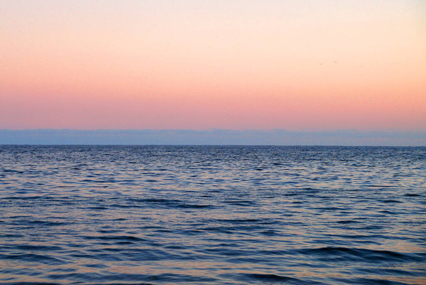 розовое небо заката, голубой горизонт и море, естественный фон. - Фото, изображение