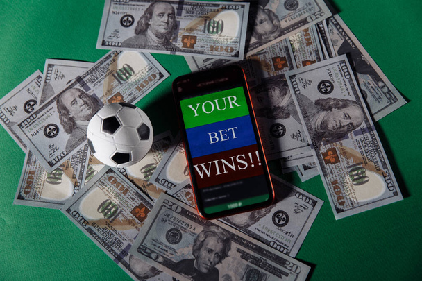ギャンブルモバイルアプリケーションとお金のクローズアップとサッカーボールとスマートフォン。スポーツ賭博の概念 - 写真・画像