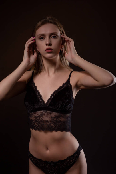 Beautiful, sexy blonde in black lace underwear on a dark background - Photo, image