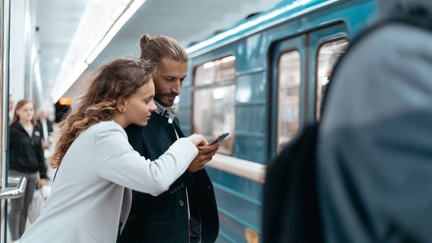 young couple with a smartphone on the subway platform . - Photo, image