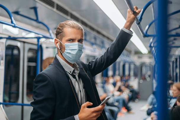 young man in a protective mask standing in a subway car. - Φωτογραφία, εικόνα