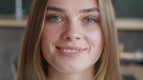 Közelkép mosolygós fiatal európai nő modell nézi kamera otthon. Portré, ha gyönyörű nő, szép arccal és kék szemekkel, egyedül áll a nappaliban. - Felvétel, videó