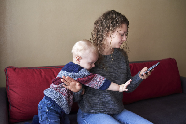 Mother is indifferent to her little son, mom looks at the smartphone, the child needs attention. The theme of parent-child relationships. - Photo, image