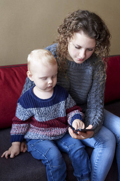 Mam laat haar zoontje zien hoe je een mobiele telefoon gebruikt, de vroege ontwikkeling van het kind. - Foto, afbeelding