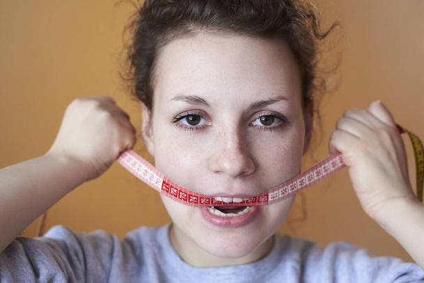 Surullinen nainen mittari suussa, aihe menettää ylipainoa, ruokavalio ja stressi. - Valokuva, kuva