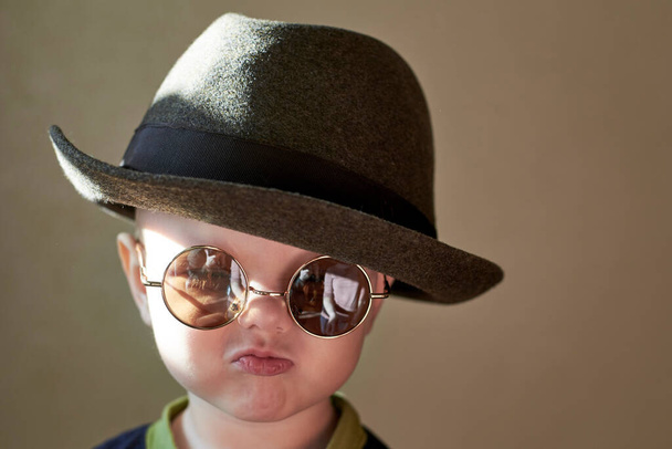Portrait of a little cute funny boy in a retro hat and round glasses. - Foto, Bild