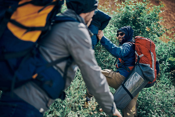 Dos exploradores con mochilas en la espalda escalando la montaña. - Foto, Imagen