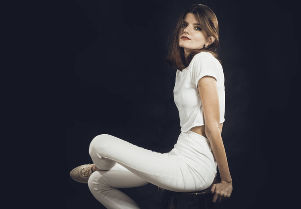Studio portrait of young beautiful woman dressed in a white jeans and t-shirt - Foto, afbeelding