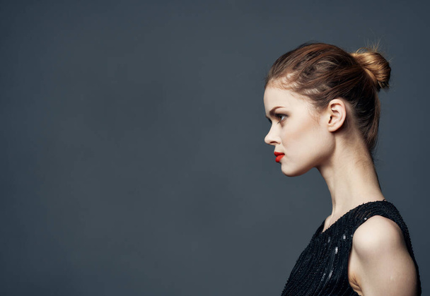 Side view of beautiful woman in black dress with hairstyle - Фото, зображення