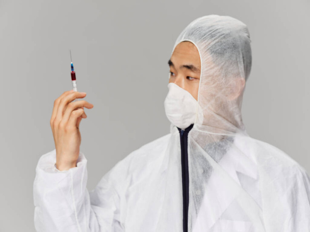 Man medical clothes syringe in the hands of the vaccine health treatment for coronavirus - Φωτογραφία, εικόνα