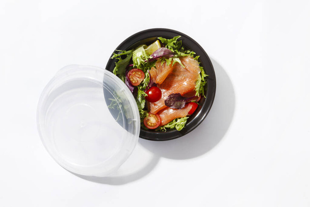 забрать коробку с салатом лосося и помидорами на белом фоне - Фото, изображение