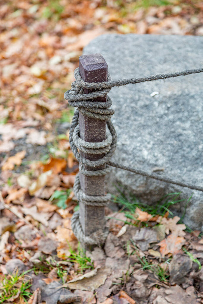 Onderdeel van een laag houten hek van houten haringen en gevlochten touwen - Foto, afbeelding