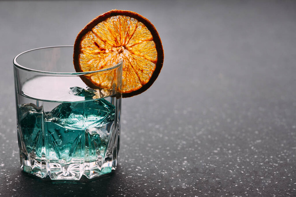 Gin w szklance z pomarańczą i lodem na czarnym tle. - Zdjęcie, obraz