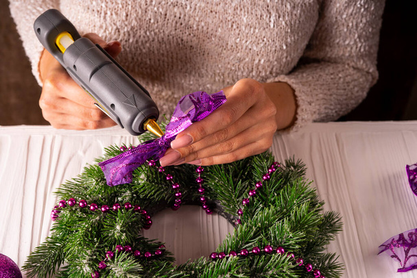 Beautiful female hands decorate a Christmas wreath. - Photo, Image