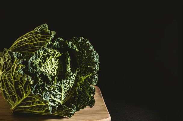 Cabbage on top of wooden board with dark background - 写真・画像