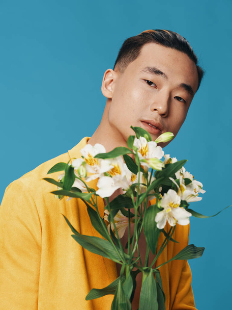 A nice guy of Asian appearance is holding a bouquet of white flowers - Foto, afbeelding