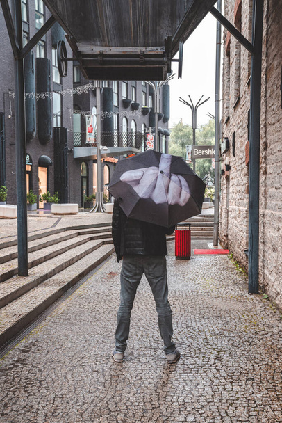 Tallinn, Estonia. June 10, 2020. Angry furious man holding umbrella with a middle finger pointing into the air towards the rain. - Фото, зображення