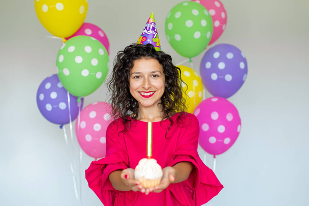 Happy Birthday. Sexy brunette girl posing with balloons, fireworks, colorful balloons and holiday cake on a white background. - Fotó, kép