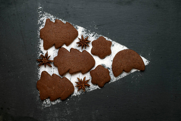 gingerbread cookies and powdered sugar on ardesia in the form of a play button - 写真・画像