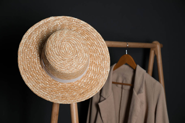 Stylish straw hat on clothing rack indoors - 写真・画像