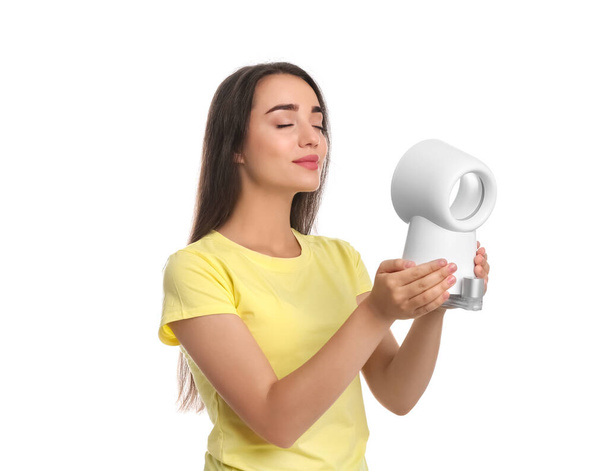 Woman enjoying air flow from portable fan on white background. Summer heat - Photo, Image