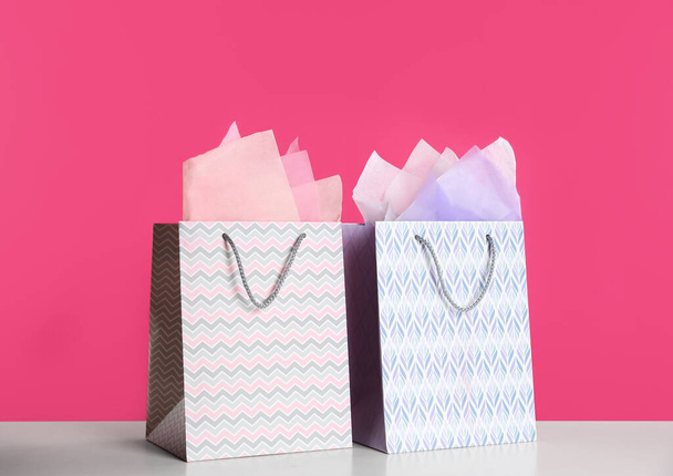 Gift bags with paper on white table against pink background - Fotó, kép