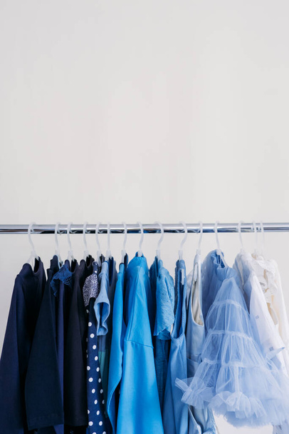Быстрая мода, устойчивая мода, минималистский гардероб. Разнообразие женской голубой одежды на белом фоне с копировальным пространством. Баннер минимального стиля моды - Фото, изображение