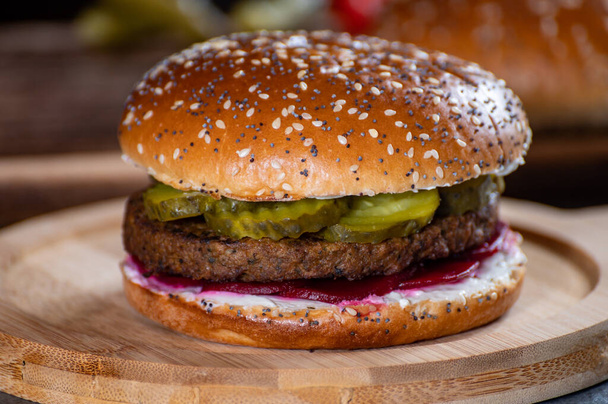 Lunch or dinner with tasty vegetarian hamburgers made from plant based grilled burgers, fresh bakes buns and organic vegetables close up - Фото, зображення