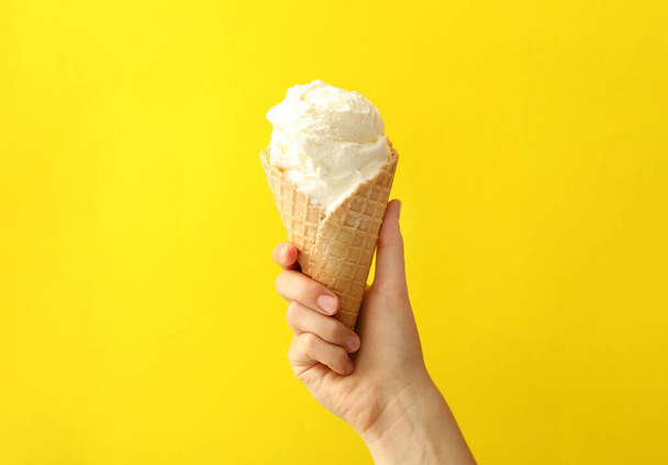 Woman holding waffle cone with delicious ice cream on yellow background, closeup - Fotografie, Obrázek