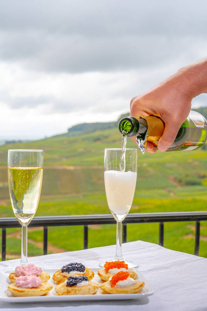 Degustazione di spumante bianco francese con champagne bollicine sulla terrazza esterna con vista sui vigneti di Champagne verdi grand cru a Cramant, vicino a Epernay, Francia - Foto, immagini