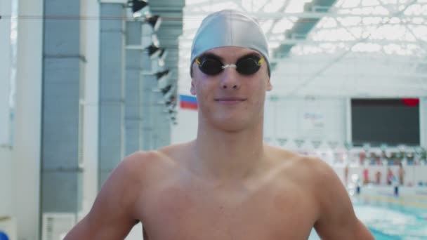 Hezký sportovec plavec s brýlemi a kloboukem se dívá do kamery a usmívá - Záběry, video