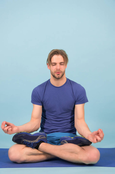 Man meditate on yoga mat. Sportsman relax in lotus pose. Fashion athlete practice yoga in gym. Meditation for body and mind health. Meditation or zen and peace concept - Photo, Image